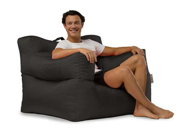 Man sitting on a large black bean bag chair against a white background