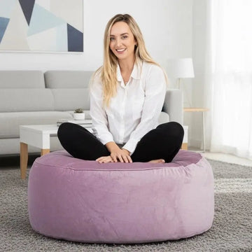 Woman sitting on a purple bean bag in a modern living room.