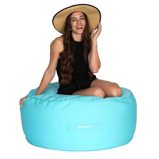 Woman wearing a straw hat sitting on a large blue bean bag ottoman.