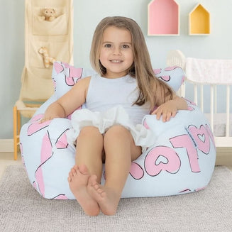 Child sitting on a bean bag with pink and white design in a room with toys and colorful boxes.